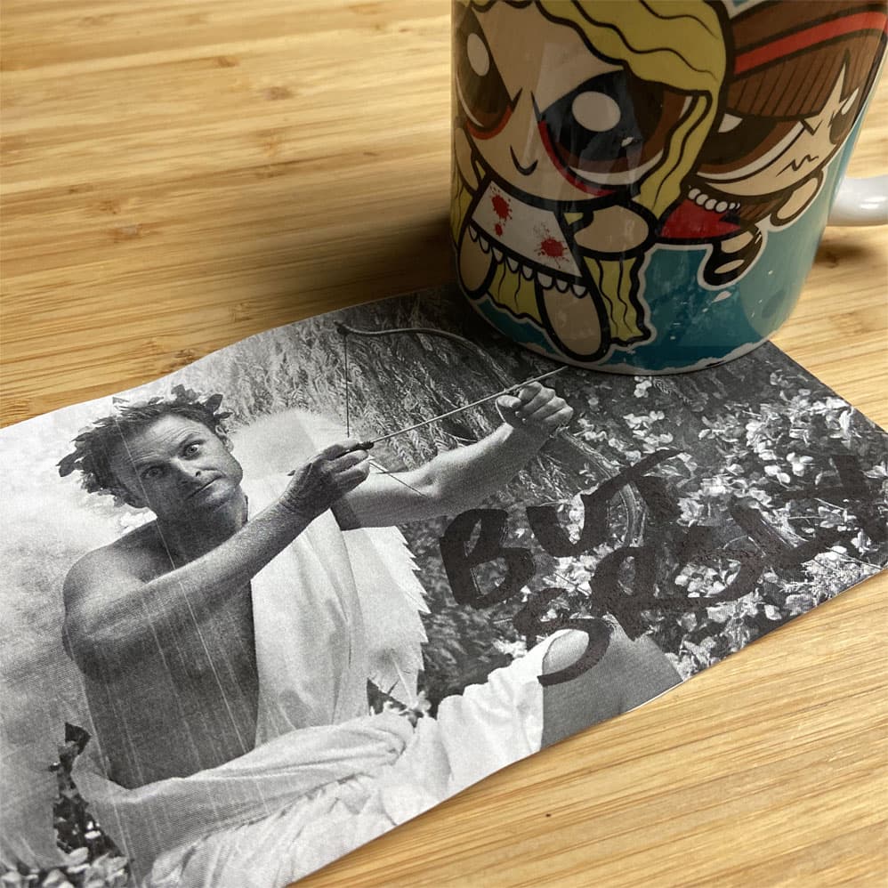 A black and white picture of Chris Harrison, dressed as cupid, with a sharpied note saying 'but srsly?', and a mug with a cartoon version of the characters from Orphan Black