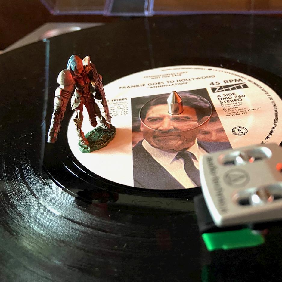 A gaming miniature figurine standing on a vinyl record of Frankie Goes to Hollywood's 'Two Tribes'
