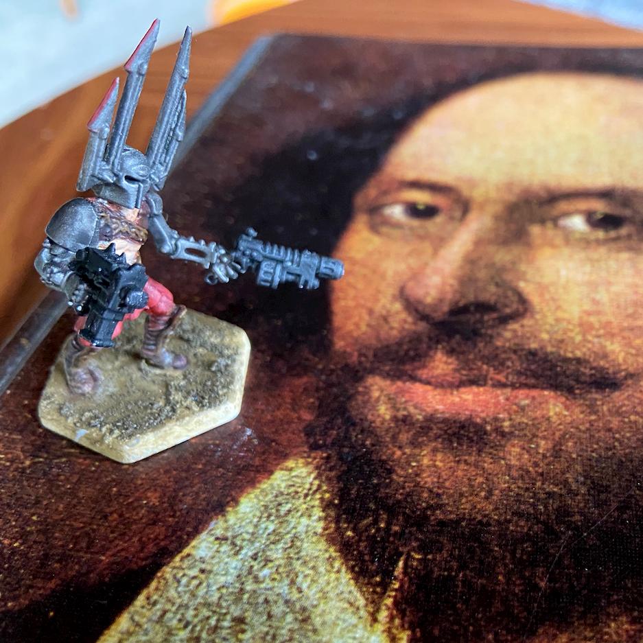 A gaming miniature figure standing on top of a picture of Shakespeare